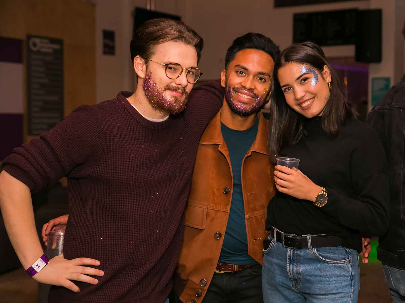Three students with their arms around each other and smiling at the camera