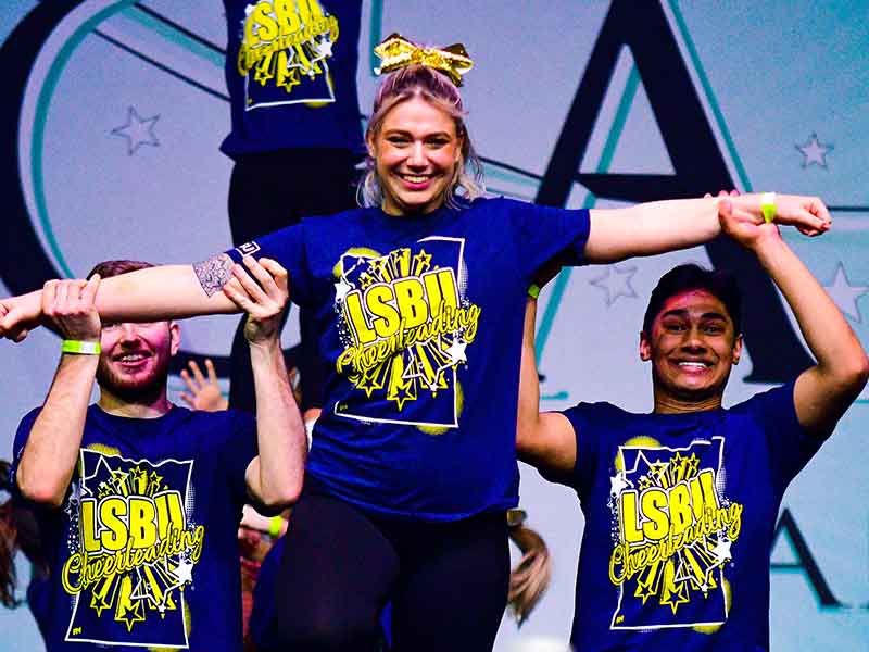 LSBSU's Cheerleading team performing a stunt and smiling at the camera