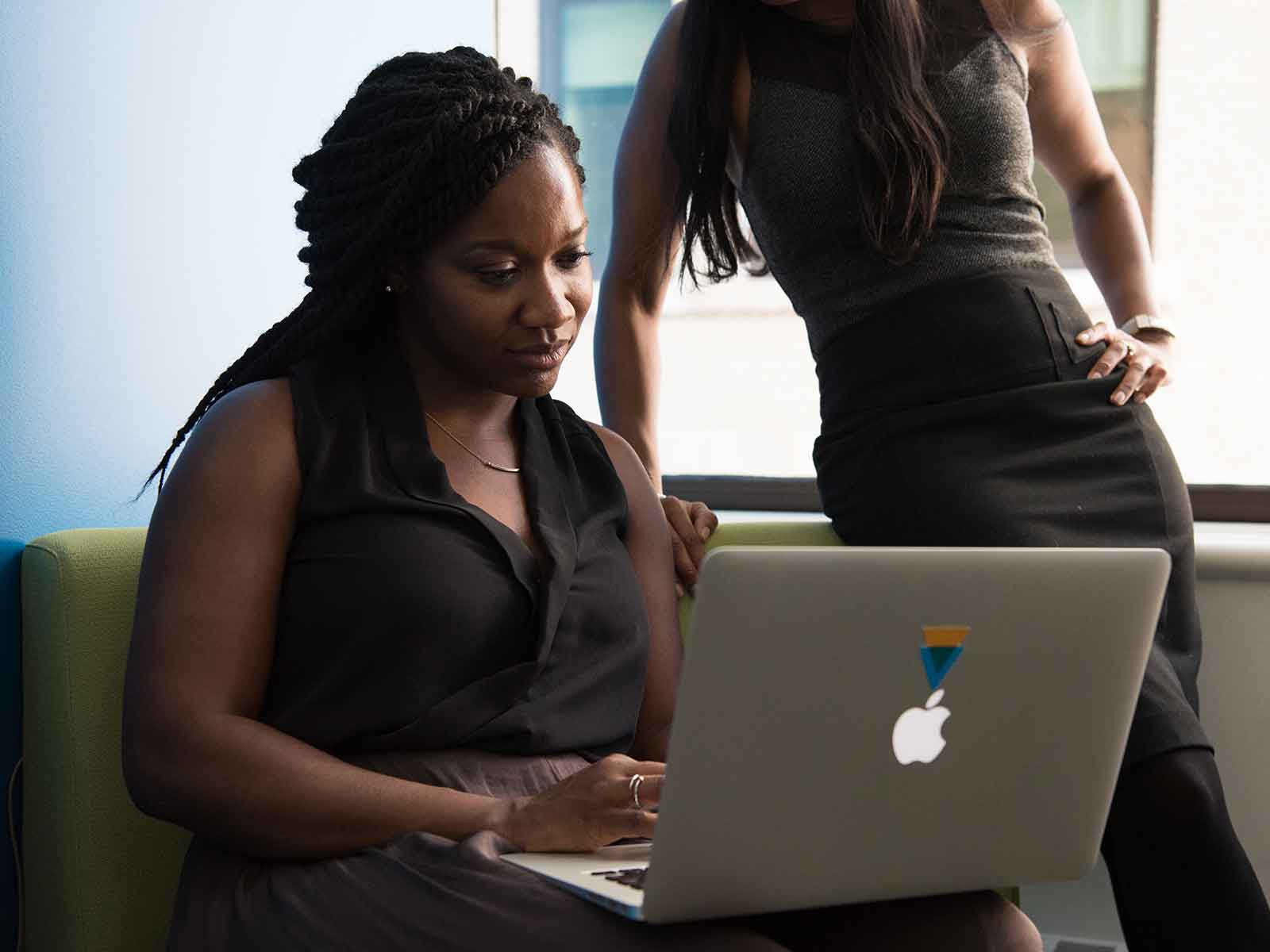 Two students talking over a laptop
