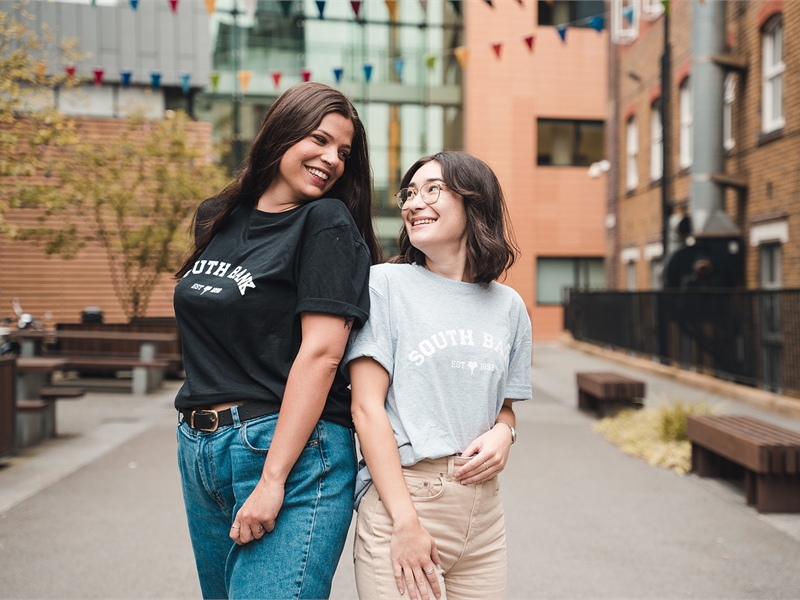 Models wearing Students' Union T-shirts and smiling at each-other